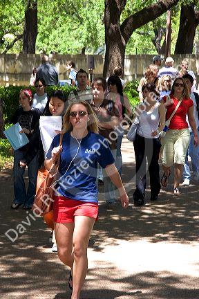 Student listening to an ipod while walking on the campus of University of Texas in Austin.