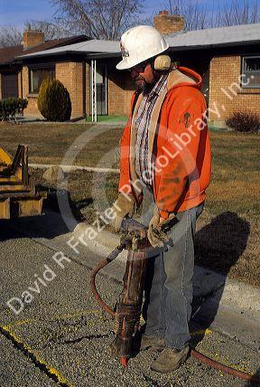 Worker with protective gear uses a jackhammer.