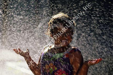 Six year old girl playing in a lawn sprinkler.