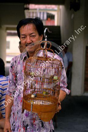 A man holds a bird cage at the Bird Market in Singapore.
