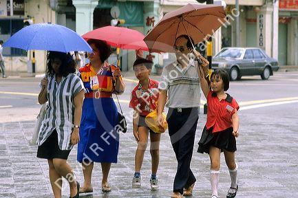 People in Singapore holding umbrellas in the rain.