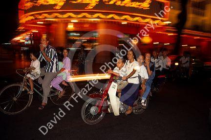 Cyclists at night in Saigon, Vietnam.  Families packed on cycles.