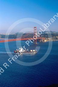 Container ship loaded with cargo passes beneath the Golden Gate Bridge at San Francisco headed out to sea.