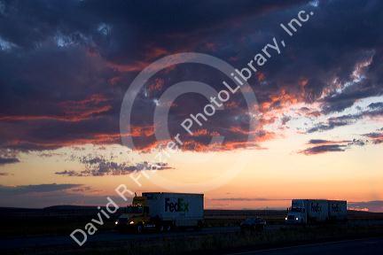 Automobiles and long haul trucks driving with headlights on at sunset on Interstate 84 east of Boise, Idaho.