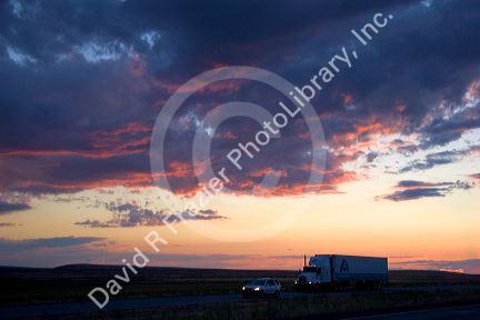 Automobiles and long haul trucks driving with headlights on at sunset on Interstate 84 east of Boise, Idaho.