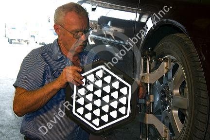Technician performing wheel alignment on automobile.