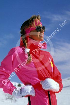 A woman snow skiing with sun glasses and nylon waterproof clothing.
