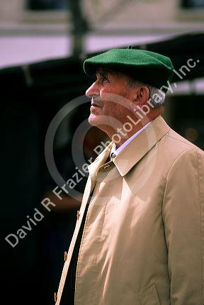 An elderly french man looking up, as if he is thinking.