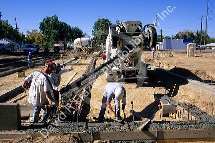 Workers pour ready-mix concrete footings for a new home foundation, Idaho.