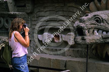 A female tourist taking a photograph of the pyramid serpent head at Teotihuacan, Mexico.