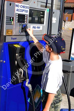 A nine year old boy pays for gasoline at the pump with a credit card in Boise, Idaho. MR
