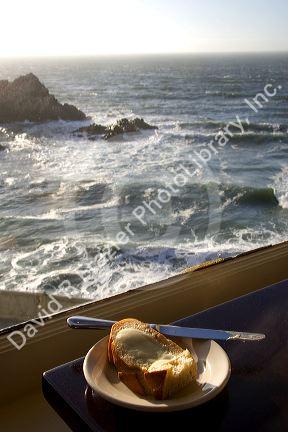 A piece of buttered bread and ocean view at The Cliff House Restaurant on the San Francisco Coast, California.