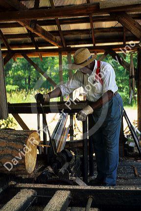 An african american man operates a sawmill at Agrirama Tifton, Georgia.