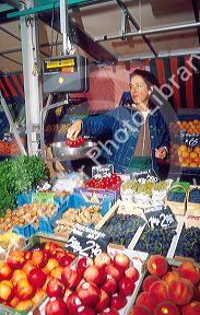 Outdoor produce market at Cologne, Germany.  German woman weighs tomato.