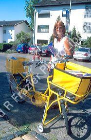 German letter carrier delivers mail on bicycle in rural village.