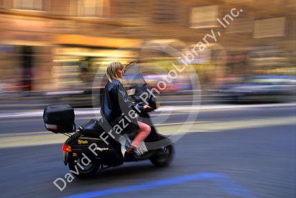 A woman rides a motor scooter in Rome, Italy.