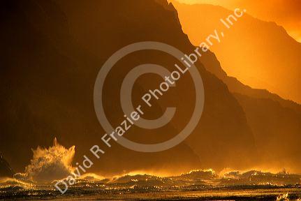 Waves crash at sunset along the Kaui coast cliffs in Hawaii.