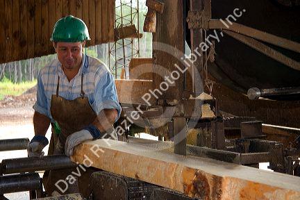 Sawyer cutting logs at a lumber mill in Argentina.