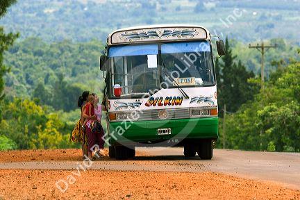 A bus stops for passengers on a rural road in Argentina.