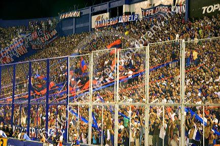 Crowds behind security fences watch a soccer game at the West Stadium in Buenos Aires, Argentina.