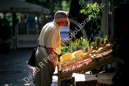 A man selects fruits and vegetables at an outdoor produce market in Munich, Germany.