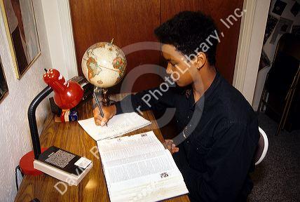 Fifteen year old african american boy doing homework and studying at home.