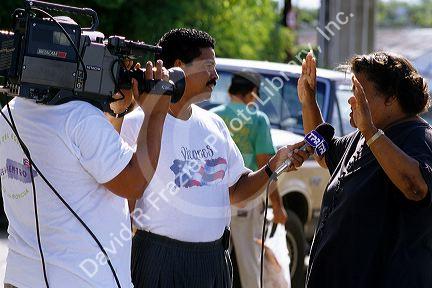 A television reporter interviews a woman in Puerto Rico.