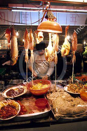 A man works at a night market selling meat and fish in Hong Kong.