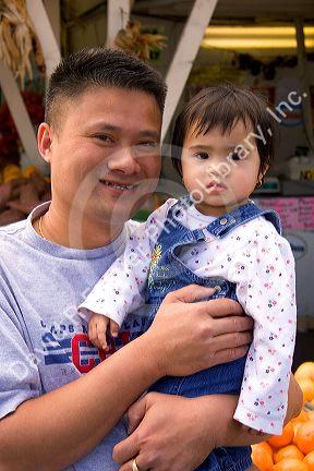 Asian father and daughter at a roadside fruit stand in Morgan Hill, California.
