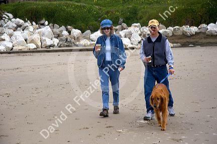Couple walking their dog on the beach in Santa Cruz, California.