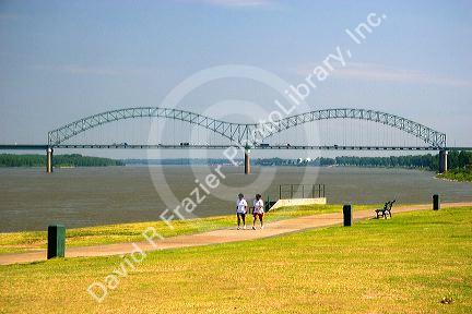 Women walk along the Mississippi River levee with the Hernando Desoto Memorial Bridge in the background at Memphis, Tennessee.