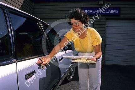 Insurance adjuster inspecting car for damage.