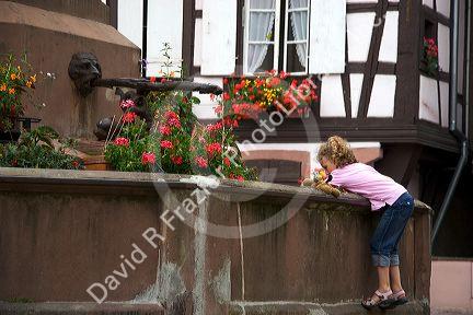 Young girl playing in a water fountain at the village of Ribeauville, Eastern France.
