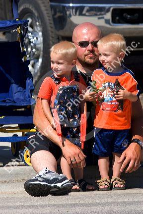Father and sons watching a small town Fourth of July parade in Cascade, Idaho.