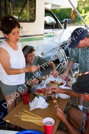 Campers preparing shish kabob meal.