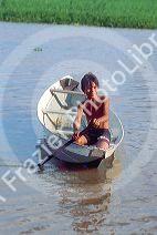 Native boy paddling his canoe on an arm of the Amazon River near Manaus Brazil.