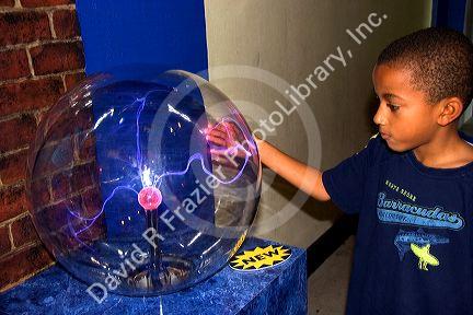 An african american boy touching a Plasma Ball at Union City Science City in Kansas City, Missouri.