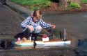 Six year old boy floating a home made model boat.  MR