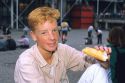 An Irish boy with red hair and freckles eats bread in Paris, France.