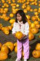 Young asian girl holding a pumpkin in a pumkin patch.