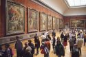 Visitors view paintings at The Louvre in Paris, France.