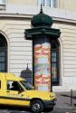 Kiosk with advertisements and a mail truck in Paris, France.
