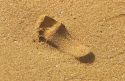 Foot print in sand on a Hawaiian beach.  Invert the image and the heel appears depressed in the sand.