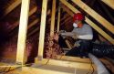 A worker blows in fiberglass insulation to the attic space of a new home.