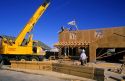 A crane lifts trusses onto the top of a new home under construction.