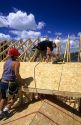 Carpenters install roof sheathing during the construction of a new home.