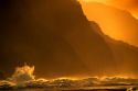 Waves crash at sunset along the Kaui coast cliffs in Hawaii.