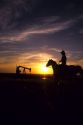 A silhouetted cowboy and oil well at sunset in North Dakota.