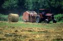A tractor pulling a round hay baler.