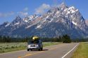 Vehicle traveling with canoe on roof on the highway through Grand Teton National Park, Wyoming.